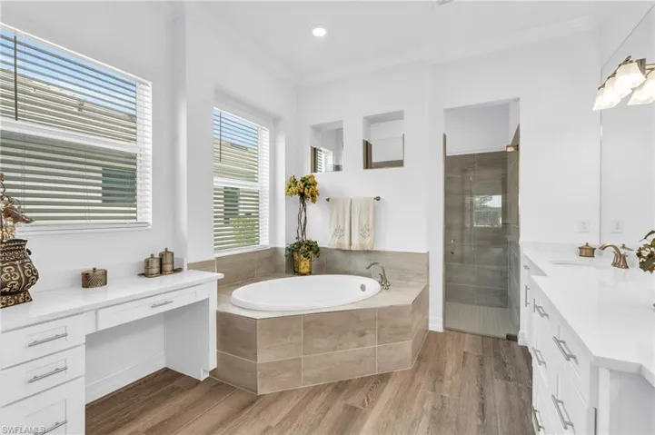 Bathroom with plus walk in shower, wood-type flooring, vanity, and crown moldingVirtually enhanced