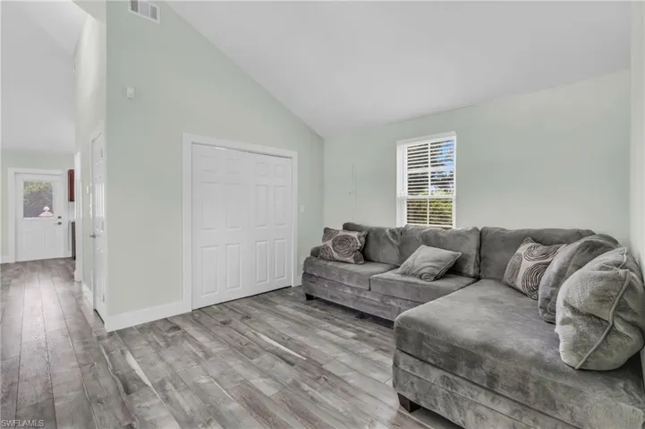 Living room with high vaulted ceiling and light wood-type flooring