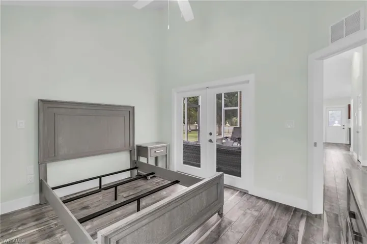 Bedroom featuring access to exterior, ceiling fan, a towering ceiling, french doors, and hardwood / wood-style flooring