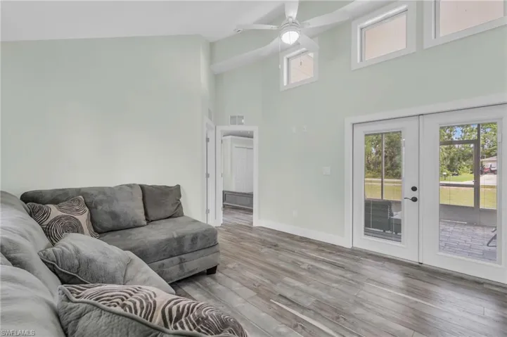 Living room with high vaulted ceiling, ceiling fan, wood-type flooring, and french doors