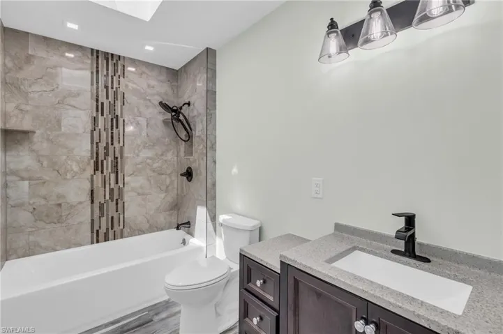 Full bathroom featuring wood-type flooring, toilet, tiled shower / bath, and vanity