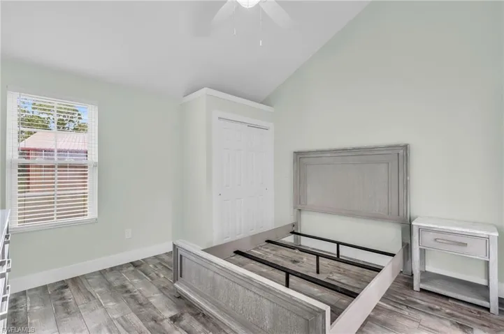 Bedroom with lofted ceiling, hardwood / wood-style floors, ceiling fan, and a closet