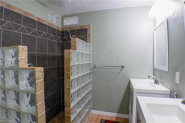 Bathroom with a tile shower, tile flooring, double sink vanity