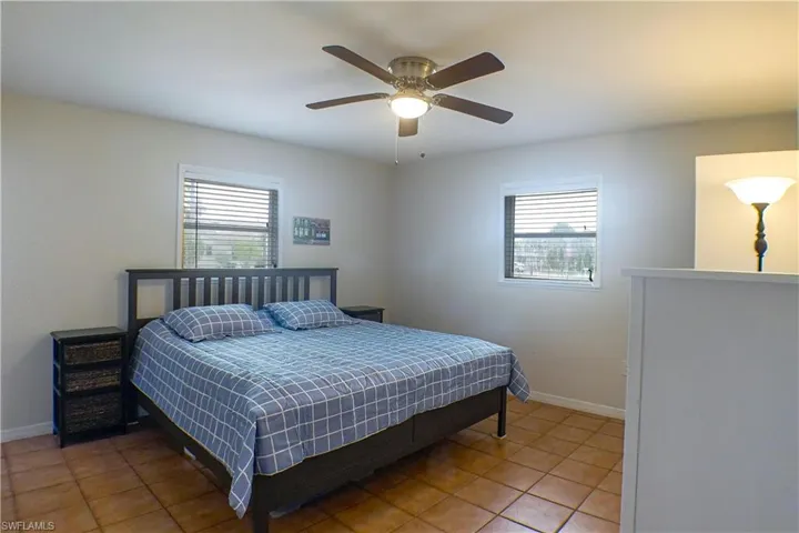 Bedroom featuring tile floors, multiple windows, and ceiling fan