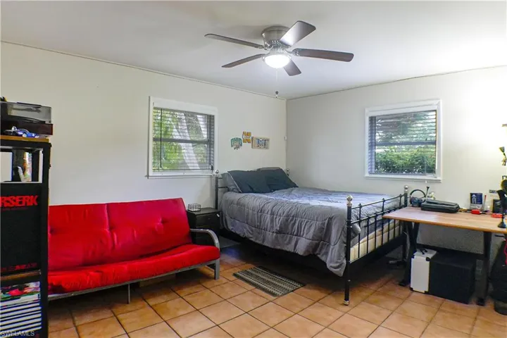 Tiled bedroom with ceiling fan and multiple windows