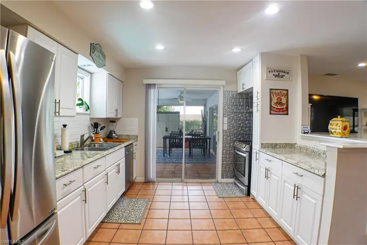 Kitchen with plenty of natural light, white cabinets, tile flooring, and appliances with stainless steel finishes
