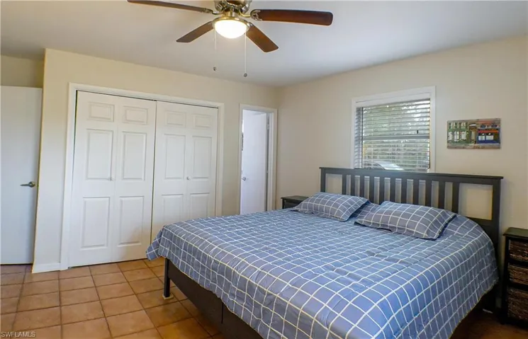 Tiled bedroom featuring ceiling fan and a closet