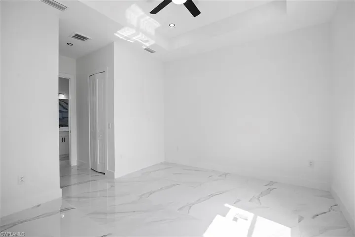 Unfurnished room with light marble finish flooring, recessed lighting, ceiling fan, and a tray ceiling