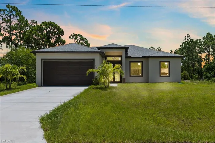 Prairie-style home featuring driveway, a front lawn, an attached garage, and stucco siding