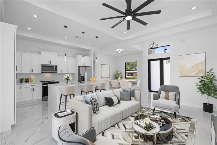 Living area featuring recessed lighting, a raised ceiling, a ceiling fan, and light marble finish floors