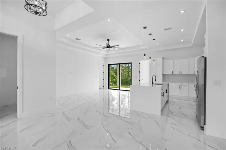 Unfurnished living room with a tray ceiling, recessed lighting, and a ceiling fan