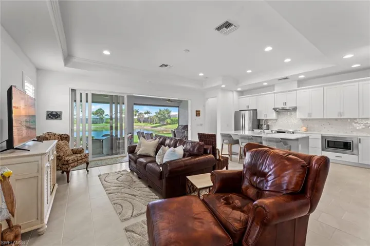 Open great room with STAGGERED TILE FLOOR, tray ceiling with crown molding, ceiling fan/light rough-in,and recessed can lights.PLANTATION SHUTTERS, and large sliders leading out to the screened lanai