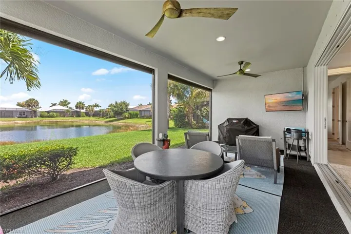 Large NO-SEE-UM SCREENED LANAI with ELECTRIC HURRICANE SHUTTERS, ELECTRIC SUN SHADE,OUTDOOR KITCHEN rough-in, ceiling fans, GRILL, MOUNTED TV, and furniture.