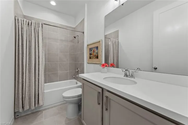 Guest bath with tub/shower tile surround, TILE FLOOR, LINEN CLOSET, and solid surface countertop with undermount sink.