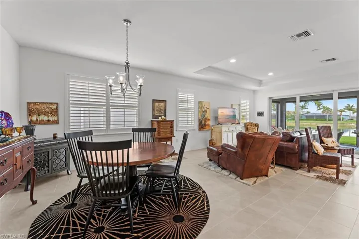 Dining area with STAGGERED TILE FLOOR and upgraded chandelier, NEW IMPACT GLASS WINDOWS (December 2020), and NEW PLANTATION SHUTTERS (June 2020)