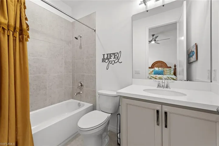 Ensuite bath with tub/shower tile surround, TILE FLOOR, and solid surface countertop with under mount sink.