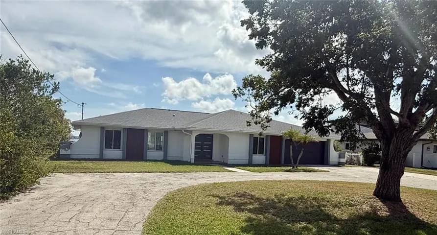 Ranch-style house featuring driveway, a front lawn, an attached garage, and stucco siding