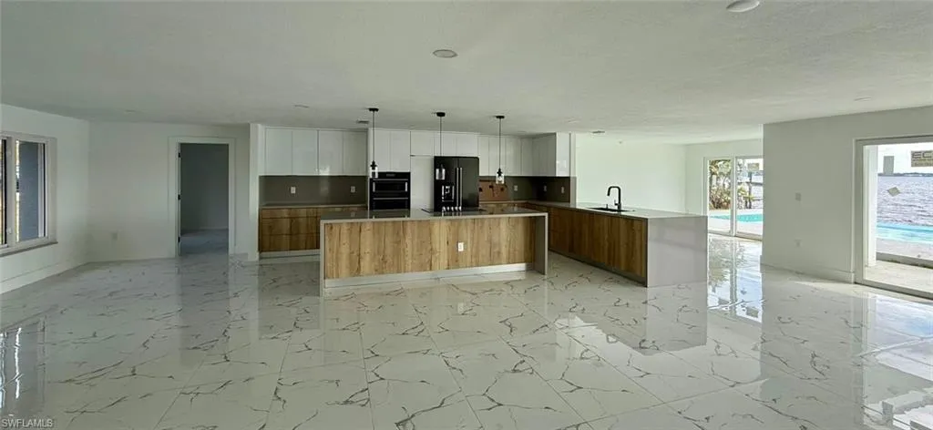Kitchen featuring modern cabinets, pendant lighting, white cabinets, and black refrigerator with ice dispenser