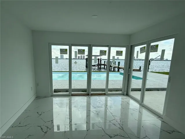 Unfurnished room featuring baseboards, marble finish floor, and a healthy amount of sunlight