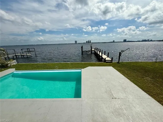 View of dock featuring a lawn, a water view, boat lift, and a pool