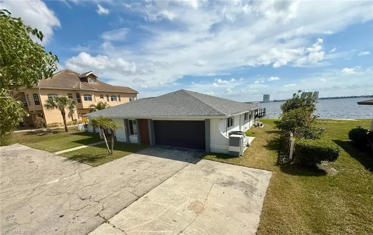 View of front of home with a front yard, a water view, driveway, and an attached garage