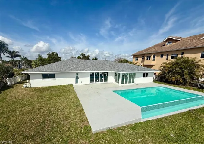 Rear view of house featuring a patio, fence, a yard, a fenced in pool, and stucco siding