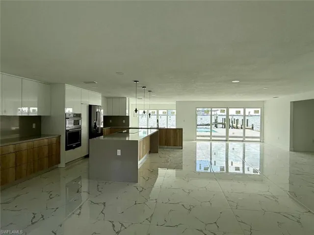 Kitchen with a center island, pendant lighting, marble finish floor, white cabinetry, and modern cabinets