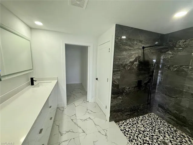 Full bathroom with recessed lighting, vanity, visible vents, marble finish floor, and a marble finish shower