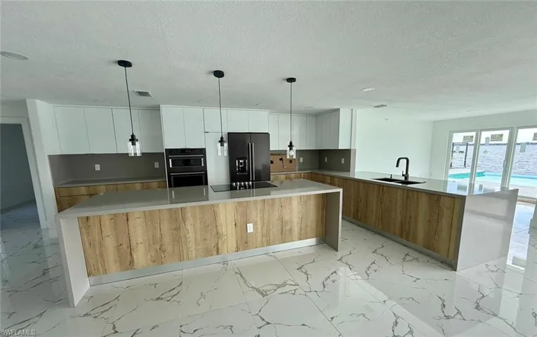 Kitchen featuring marble finish floor, light countertops, black appliances, white cabinetry, and a sink