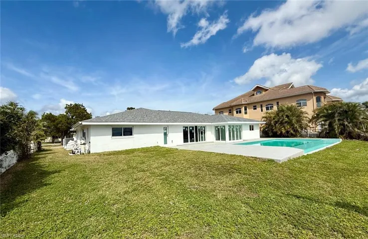 Back of property with a yard, a patio, stucco siding, and an outdoor pool