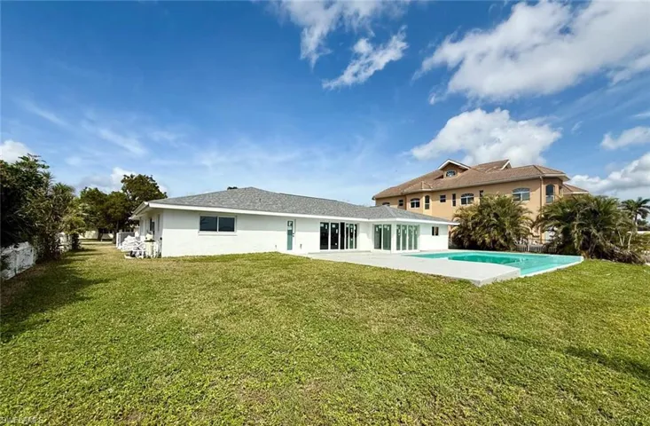 Back of house with an outdoor pool, a lawn, and a patio
