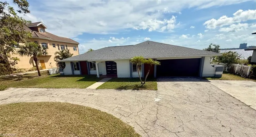 View of front of house with a garage, aphalt driveway, a front yard, and fence