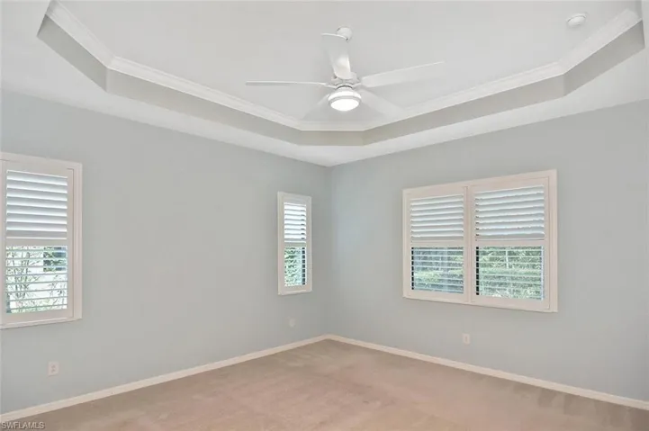 The light and bright Primary bedroom with tray ceiling and Plantation shutters