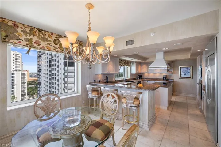 Dining room with a tray ceiling, hanging lights, and light tile patterned flooring