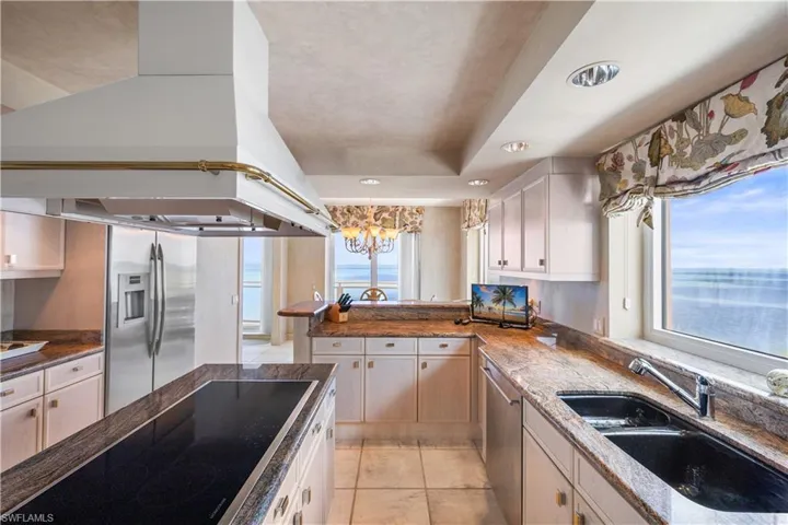 Kitchen featuring stainless steel appliances, recessed lighting, light tile patterned floors, dark stone counters, and white cabinetry