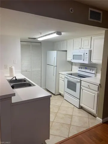 Kitchen with white cabinetry, sink, and white appliances