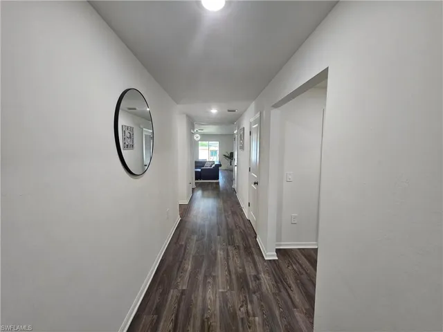 Hall featuring dark wood-style flooring and baseboards