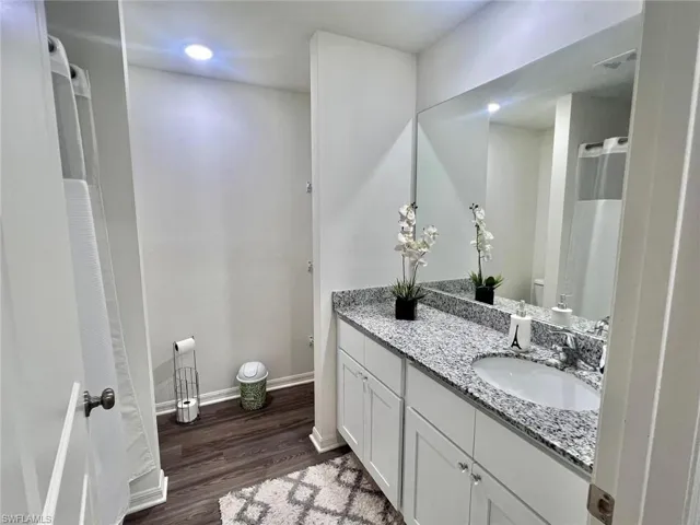 Full bath featuring curtained shower, dark wood-type flooring, vanity, and recessed lighting