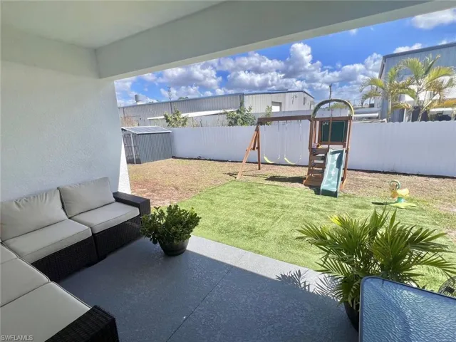 Fenced backyard with an outdoor living space, a patio area, a playground, and a storage shed