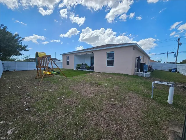 Back of house with a fenced backyard, a patio, stucco siding, and a playground