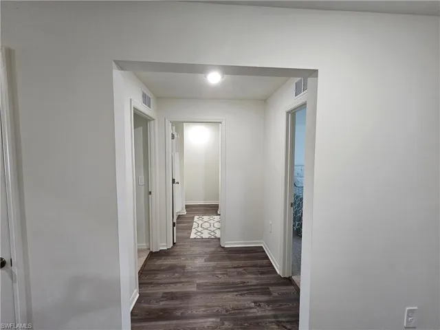 Hall with dark wood-style floors and baseboards