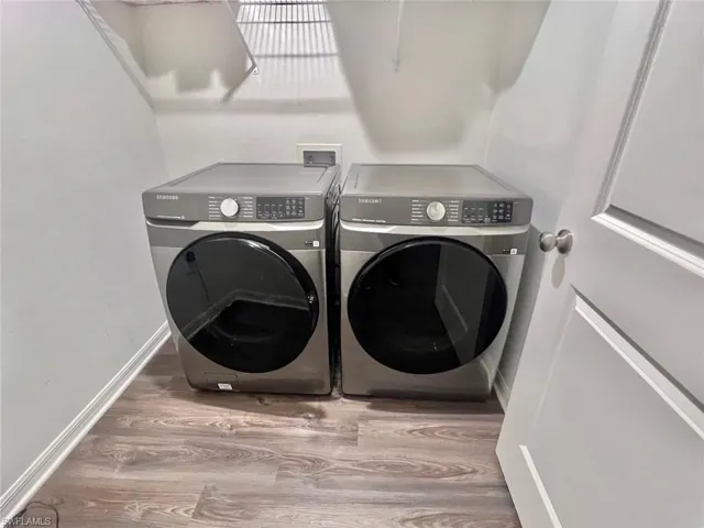 Laundry room with light wood-type flooring and washing machine and clothes dryer