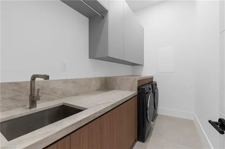 Laundry room with separate washer and dryer, light tile patterned floors, and cabinet space