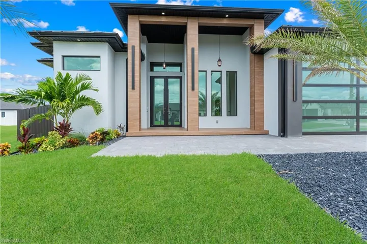 Rear view of property with stucco siding, french doors, and a yard