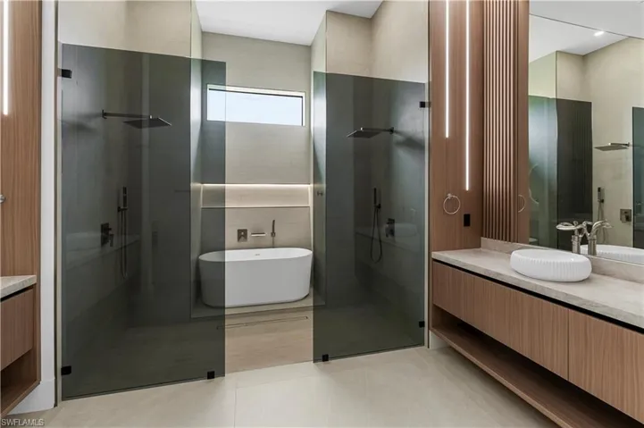Full bathroom with vanity, a freestanding bath, a shower stall, and light tile patterned floors