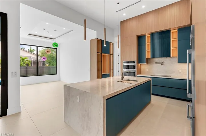 Kitchen with light stone countertops, modern cabinets, decorative light fixtures, decorative backsplash, and recessed lighting