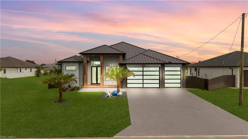 Modern home featuring a metal roof, a standing seam roof, driveway, and an attached garage