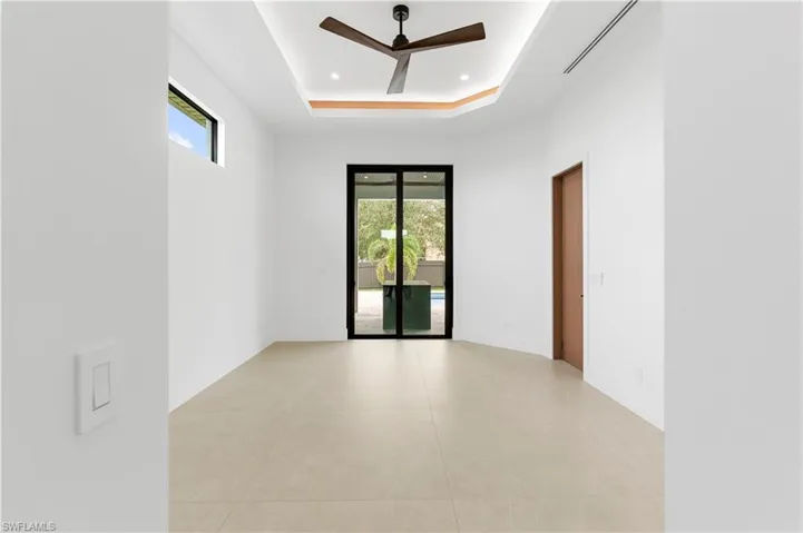 Unfurnished room featuring a raised ceiling, ceiling fan, light tile patterned flooring, and recessed lighting