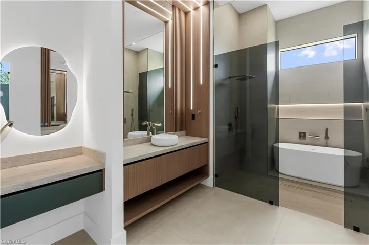 Full bathroom with a freestanding bath, a shower stall, vanity, and light tile patterned floors
