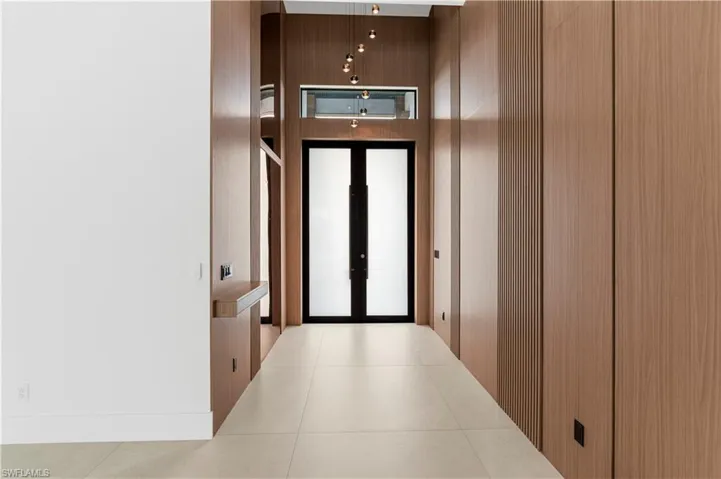 Hallway featuring tile patterned floors and wood walls